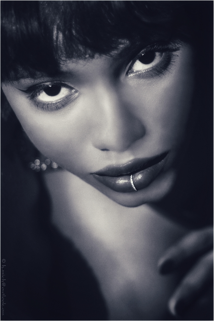 Diarium.Studio-One.Art.Br A close-up black and white portrait of a person with intense eyes. They have dark hair and a lip ring, and are gazing upward. The focus is on their expressive facial features and piercing look. (c) H.Mich
