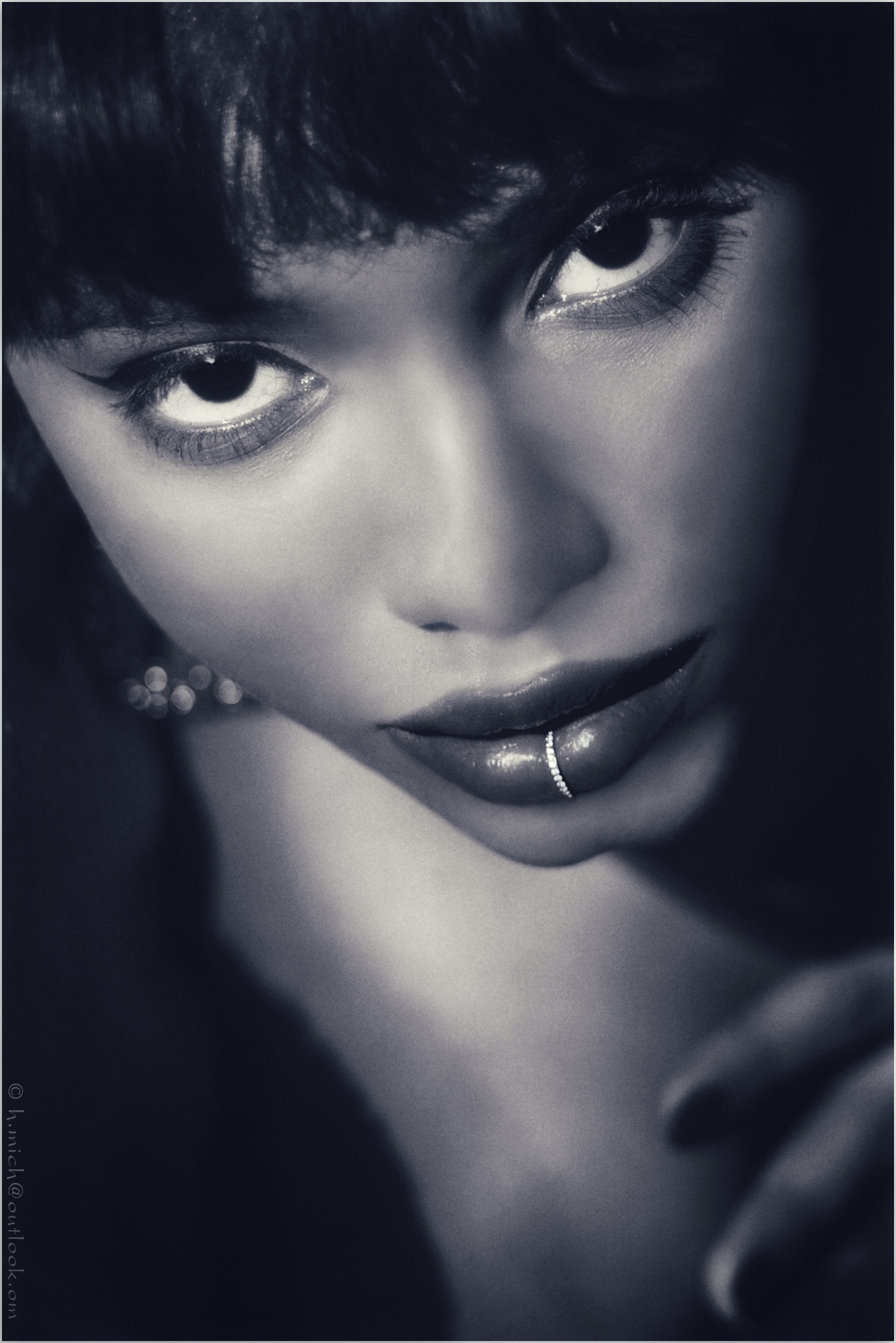 Diarium.Studio-One.Art.Br A close-up black and white portrait of a person with intense eyes. They have dark hair and a lip ring, and are gazing upward. The focus is on their expressive facial features and piercing look. (c) H.Mich
